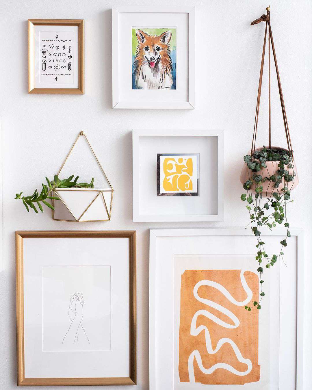Kunstwerke und hängende Pflanzen, die eine eklektische Galeriewand bilden