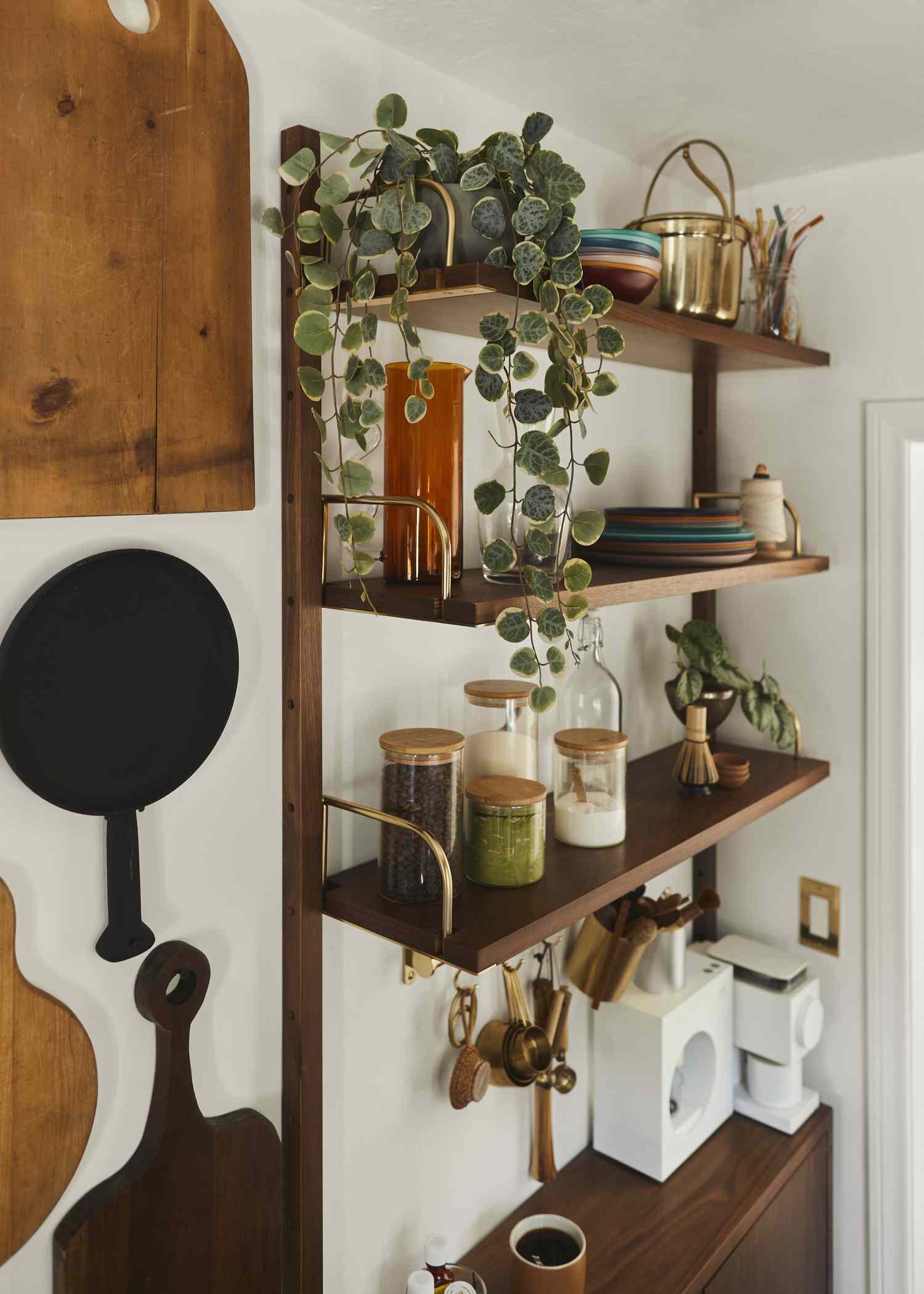 Offene Holzregale in einer Küche mit Geschirr, Pflanzen und Accessoires darauf