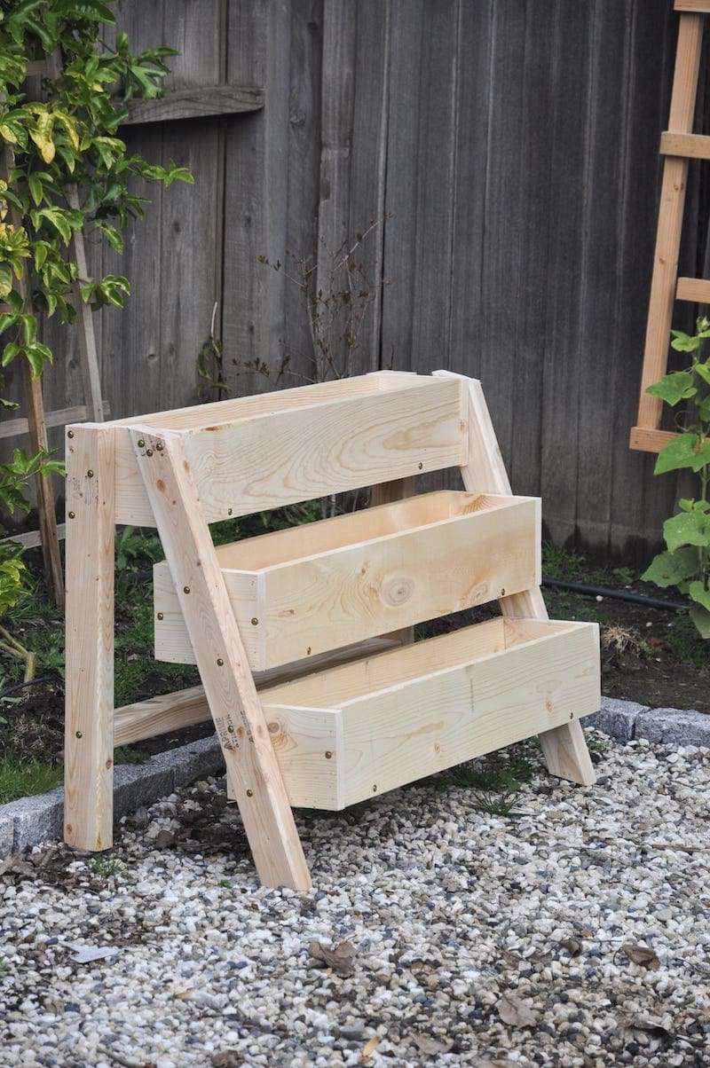 Ein stufenförmiger Pflanzkasten aus Holz auf Kies.