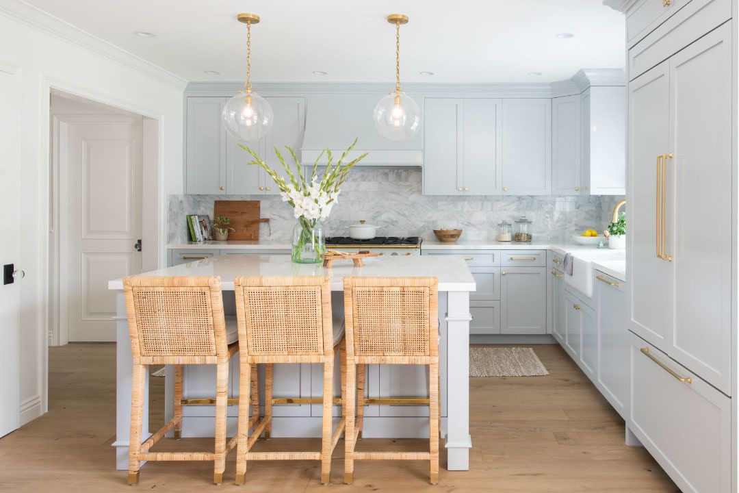 Küstenküche mit hellblauen Schränken, Glasanhängern und Rattan Counter Stools