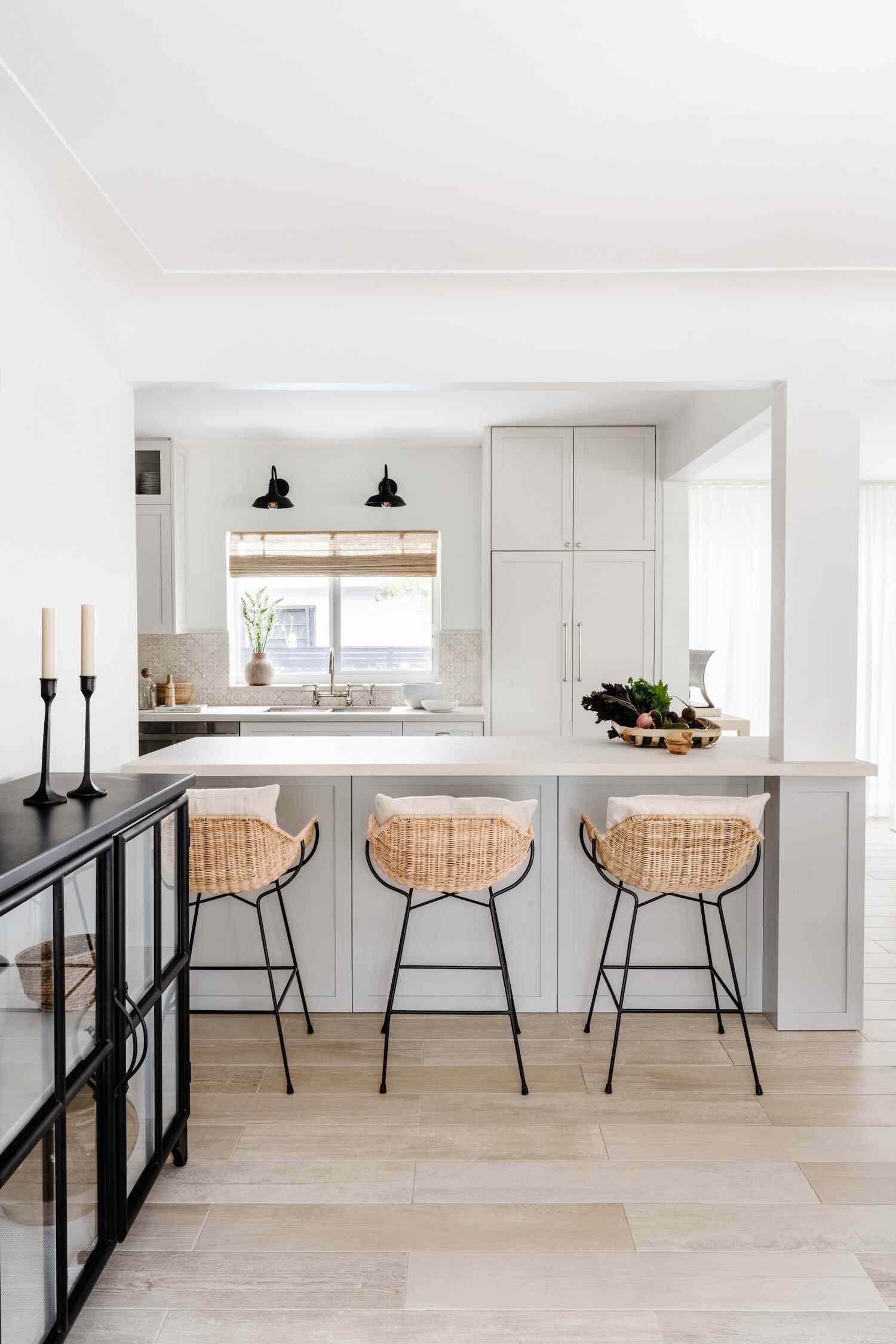 Moderne Küstenbauernküche mit außerhalb weißen Schränke, schwarzen Wandleuchten und Rattan Counter Stools