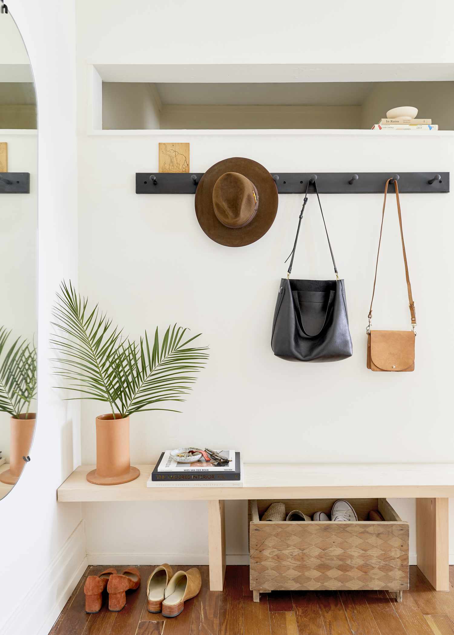 A light pink bench site below a long line of racks to hang coats and hats