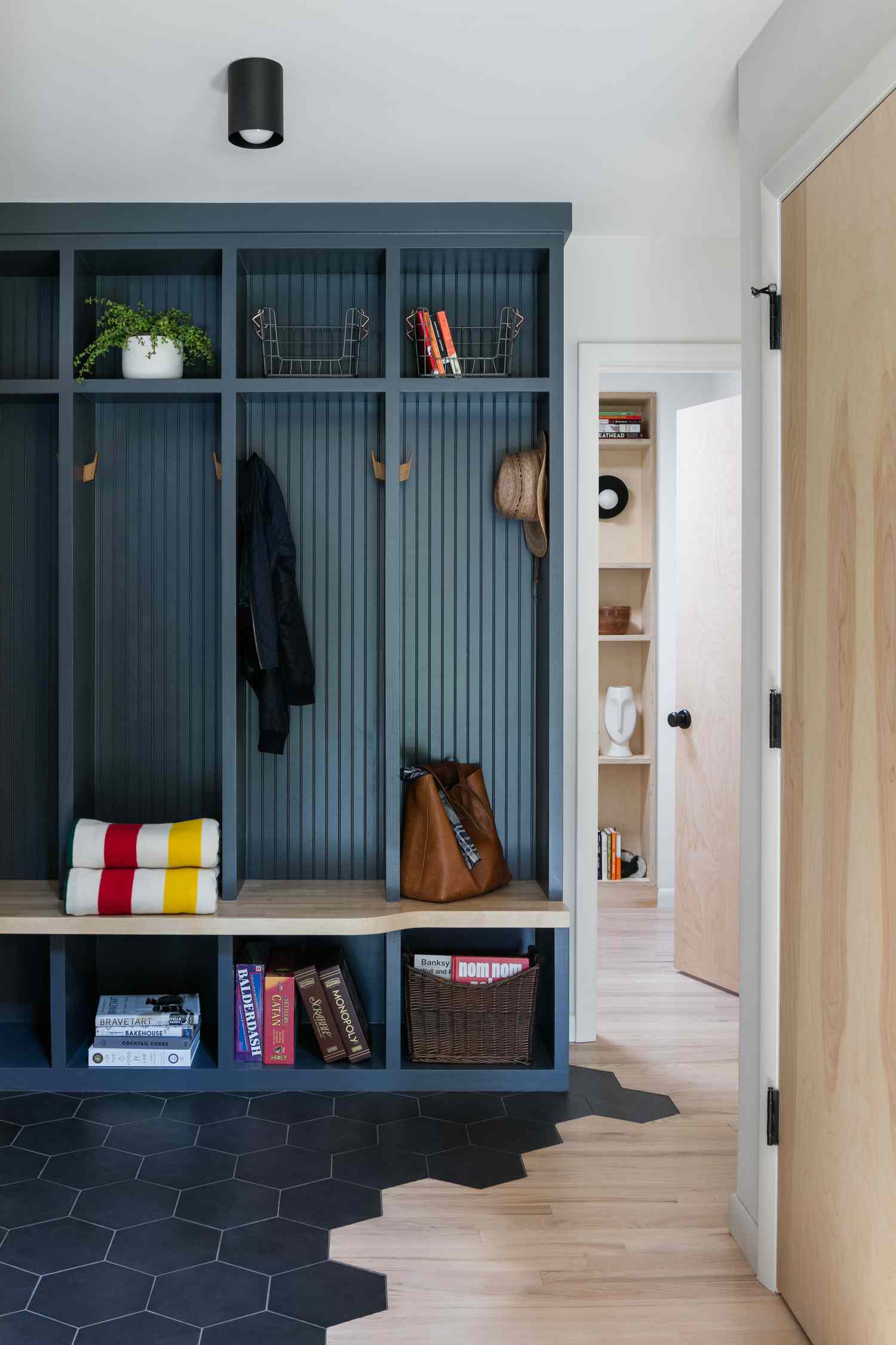 Bright aqua mudroom built-in cubbies are paired with dark blue floor tile. 