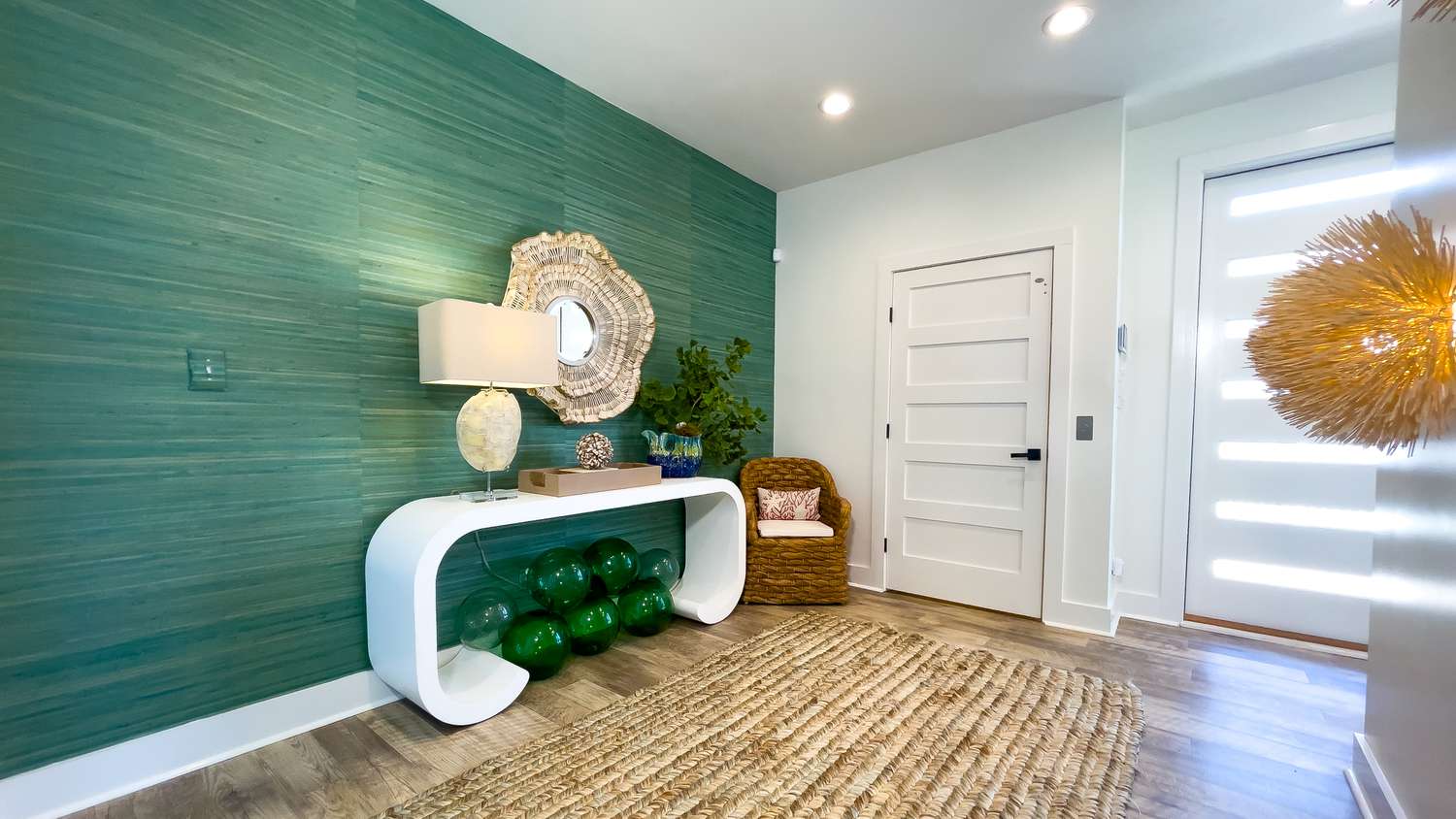 A bright green accent wall is paired with the rest of the room's white walls. The green wall has a modern white side table covered in modern artwork.