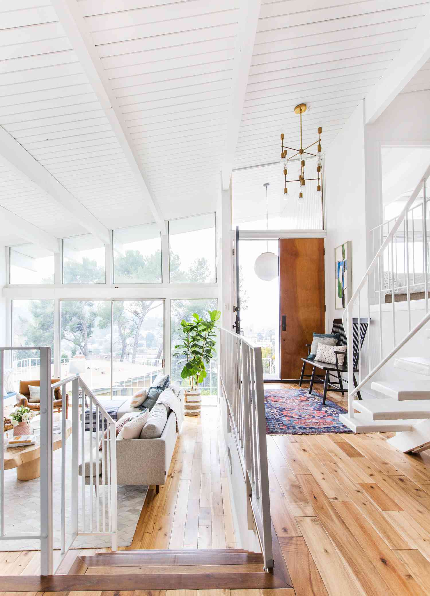 A white room has a wood floor with an entryway ground covered in a long bright rug