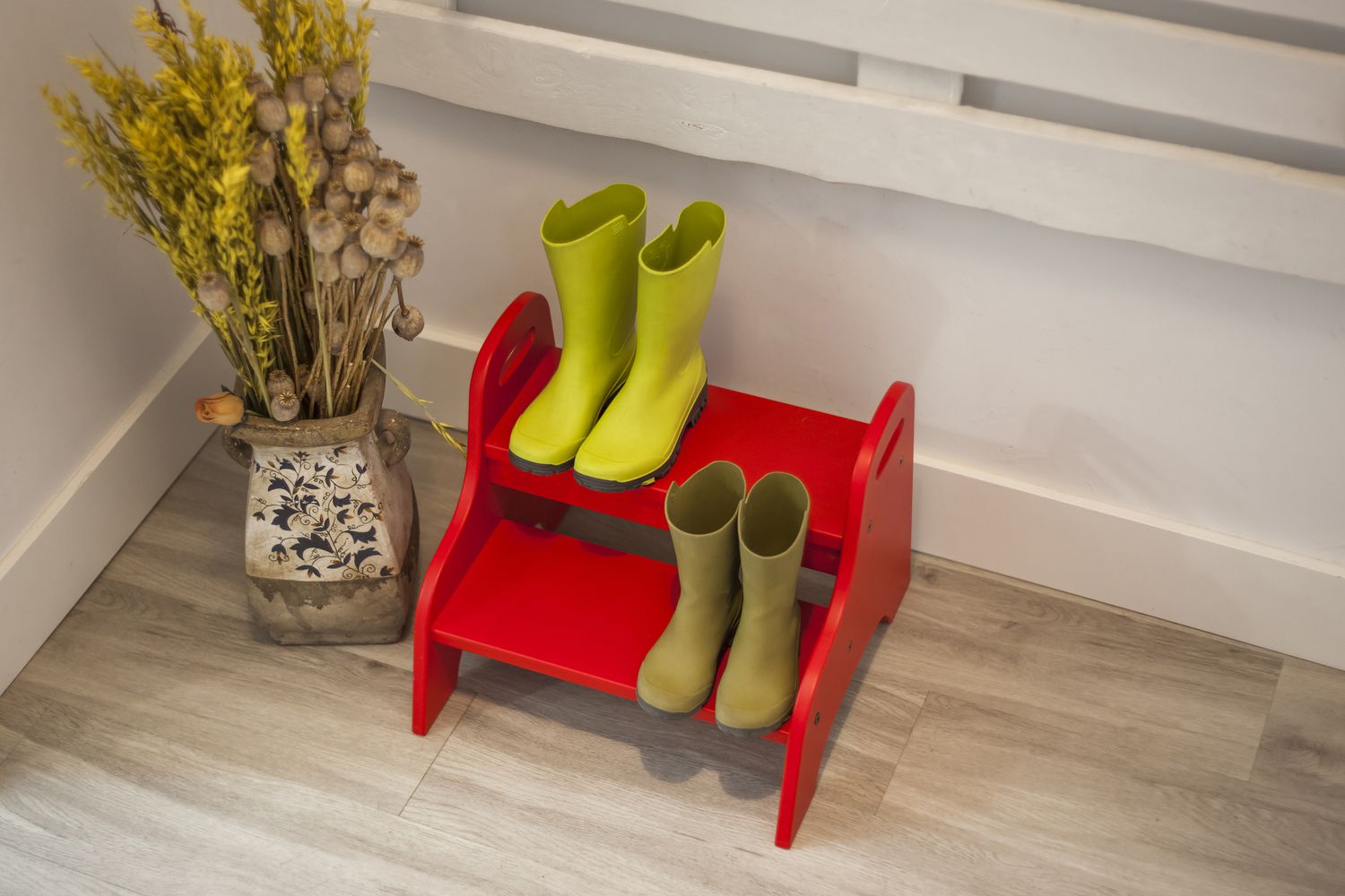 A red step stool with rainboots