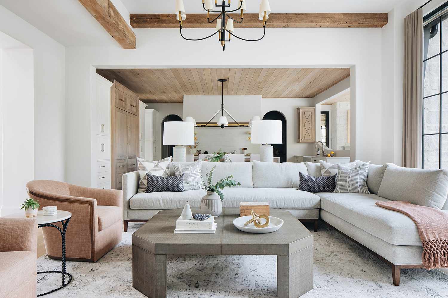 Living room with kitchen in the background with wood planked ceiling