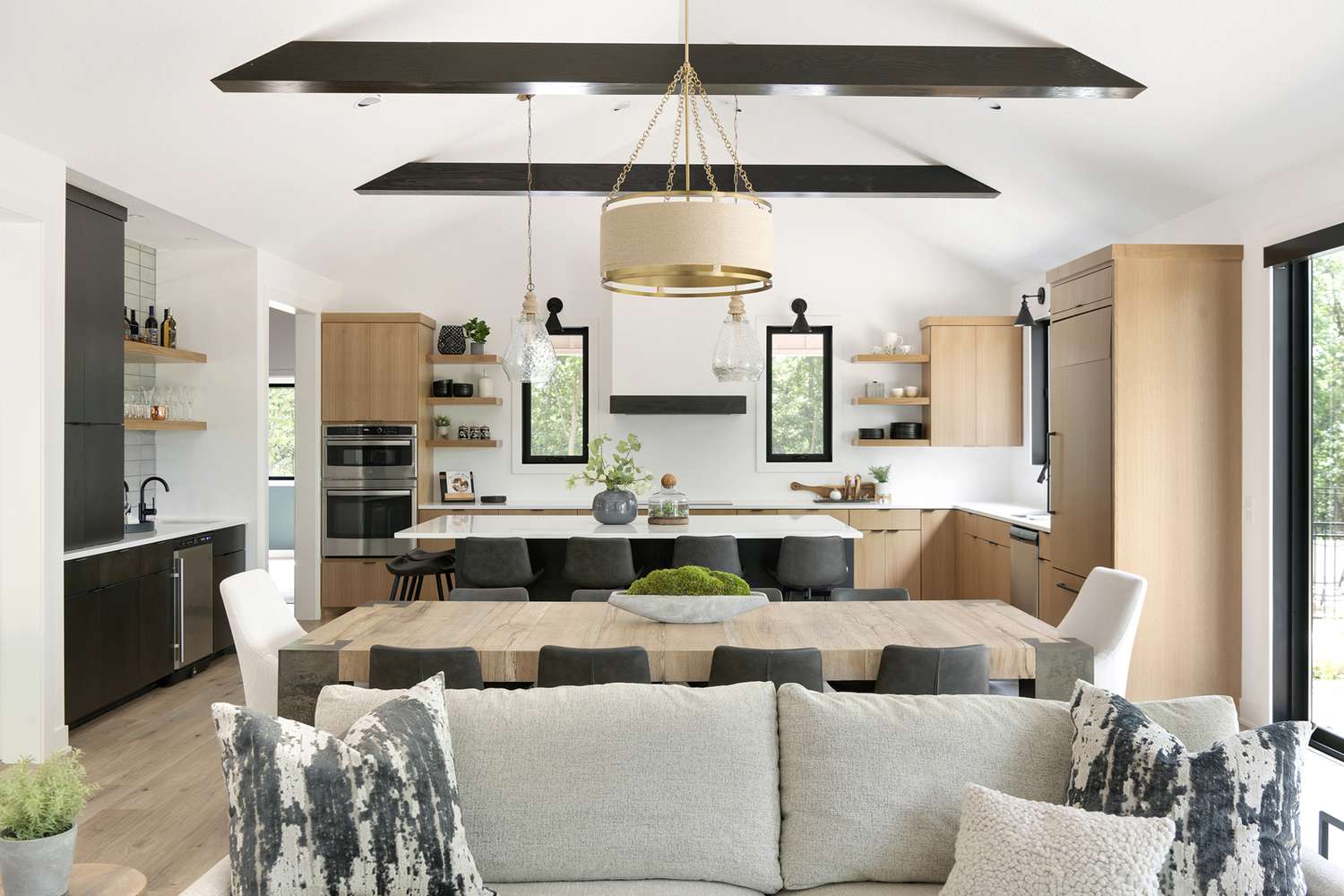 Neutral colored opening living room and kitchen with wood ceiling beams