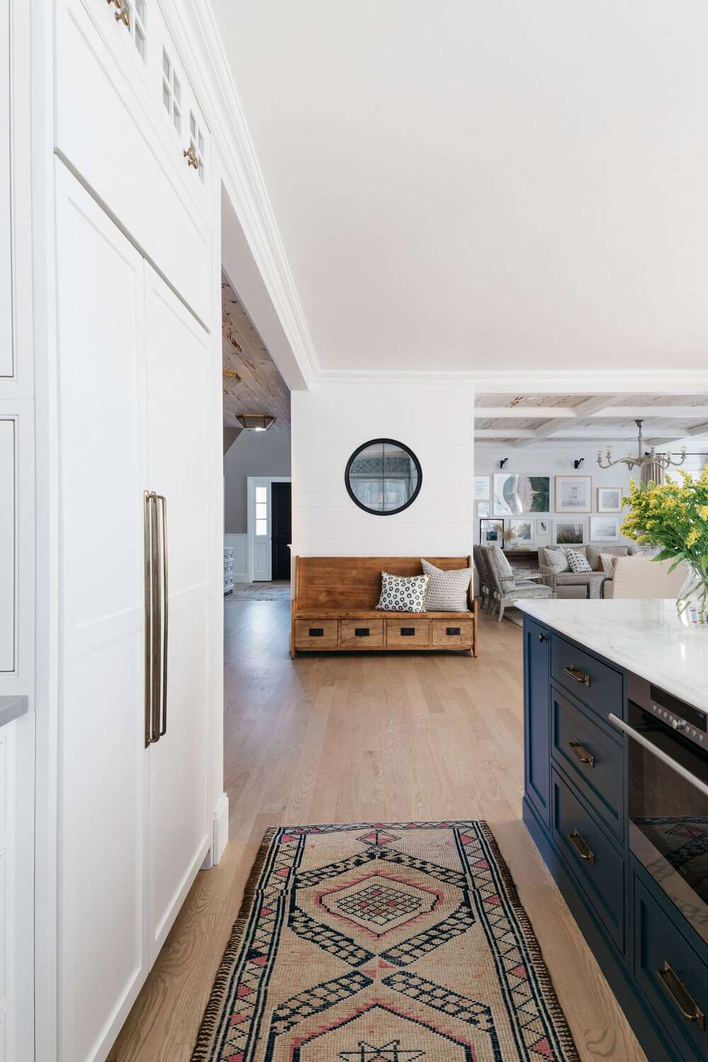 Kitchen with blue island and entryway bench and living room in the background