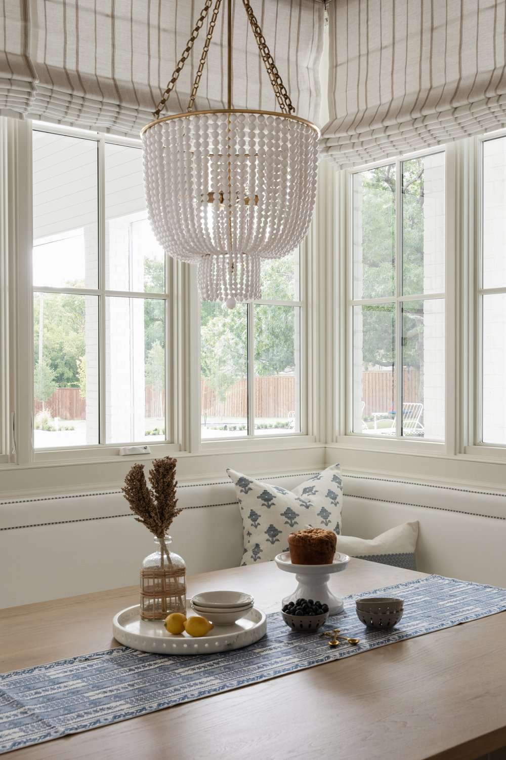 Sunroom breakfast nook with striped window shades and a beaded chandelier