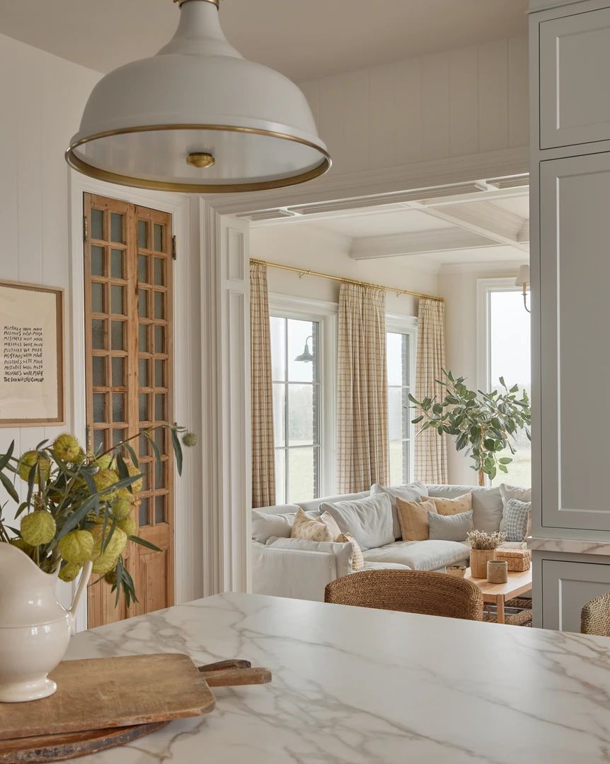 Patterned curtain panels in a white sunroom with a potted tree in the corner and a deep sectional