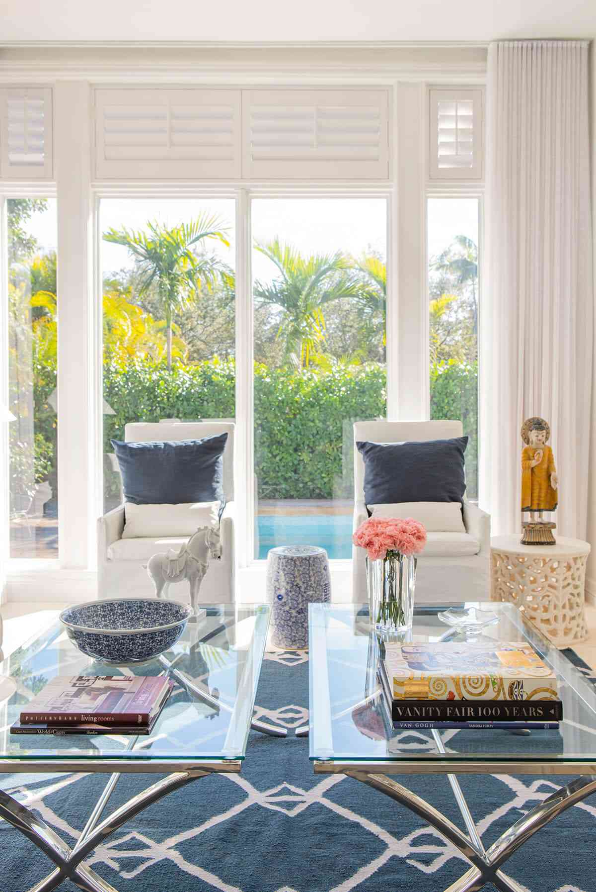 Patterned area rug under two glass coffee tables in a modern sunroom