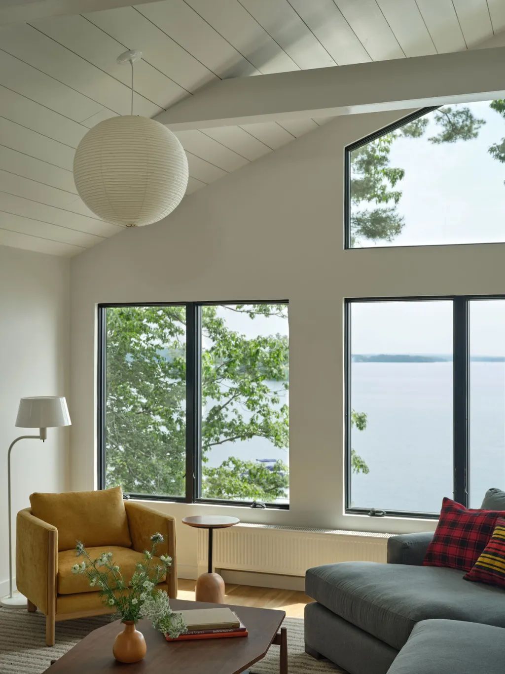 Sunroom with white shiplap ceiling, tall windows and modern furniture