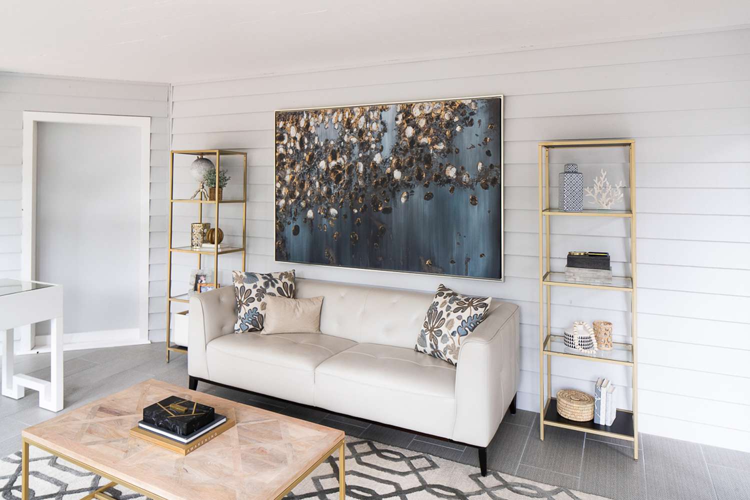 Large abstract piece of art above an off-white sofa in a small sunroom