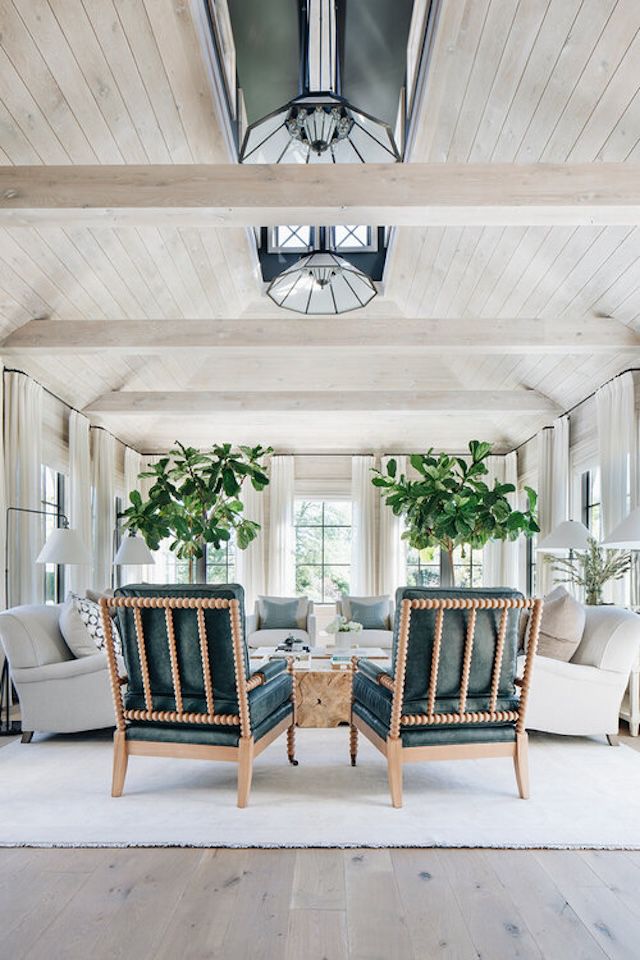 Sunroom with two tall potted trees and neutral colored furniture