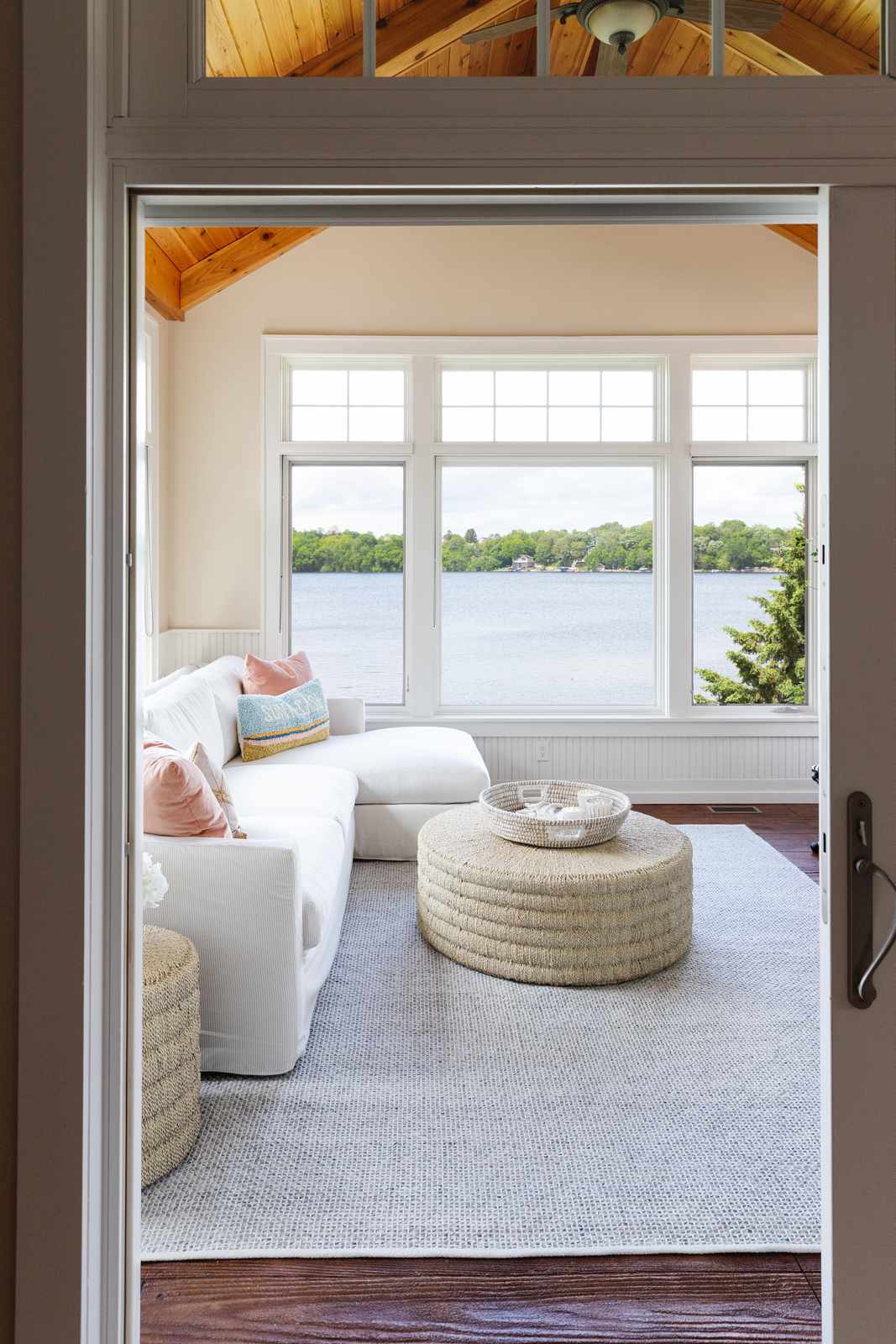 Sunroom with vaulted wood ceiling, cream walls and a white sectional