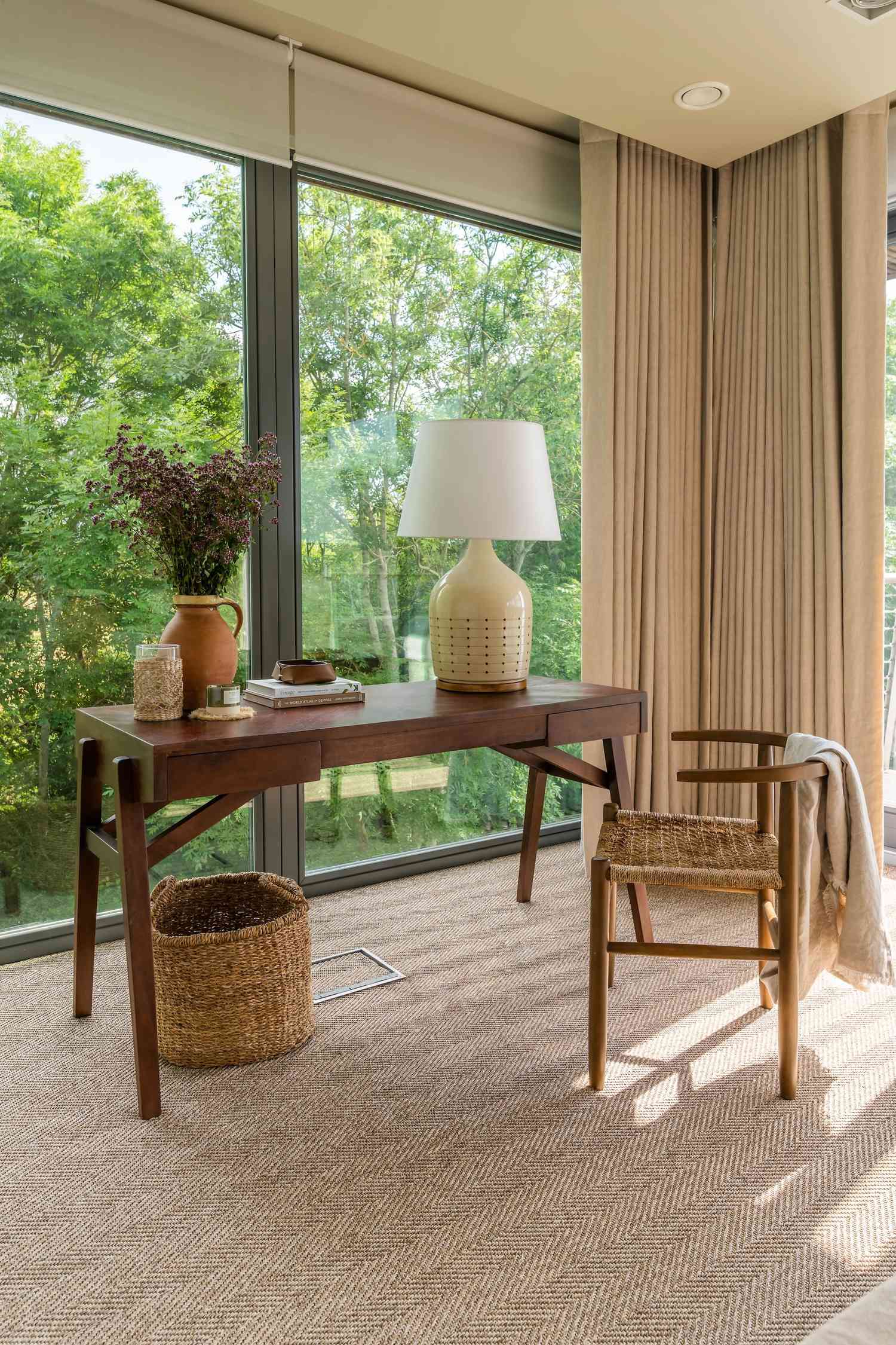 Window blinds and floor to ceiling curtains in a sunroom with a wood desk and chair in front of the window