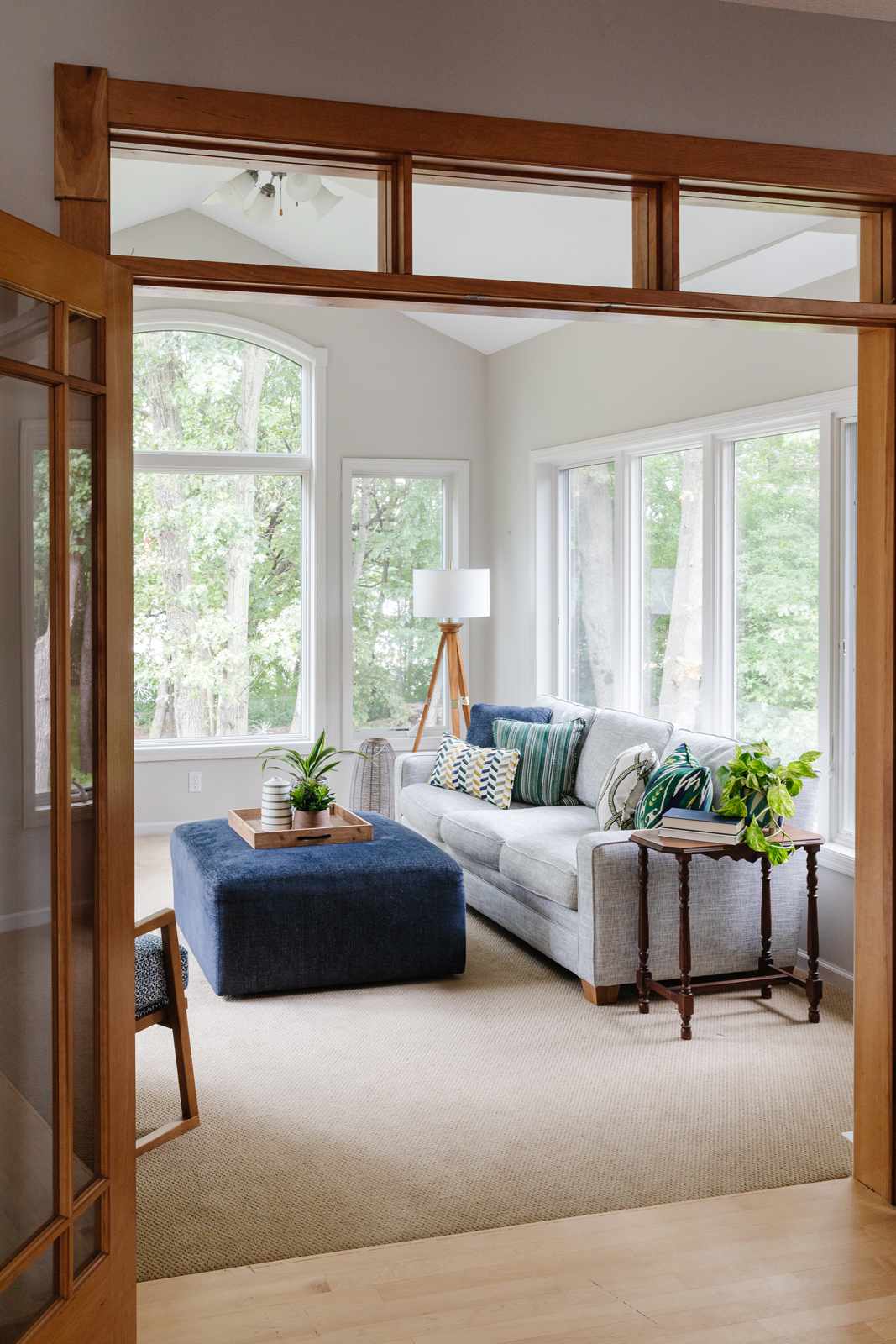 Light gray walls in a sunroom with large windows, gray sofa and blue ottoman coffee table