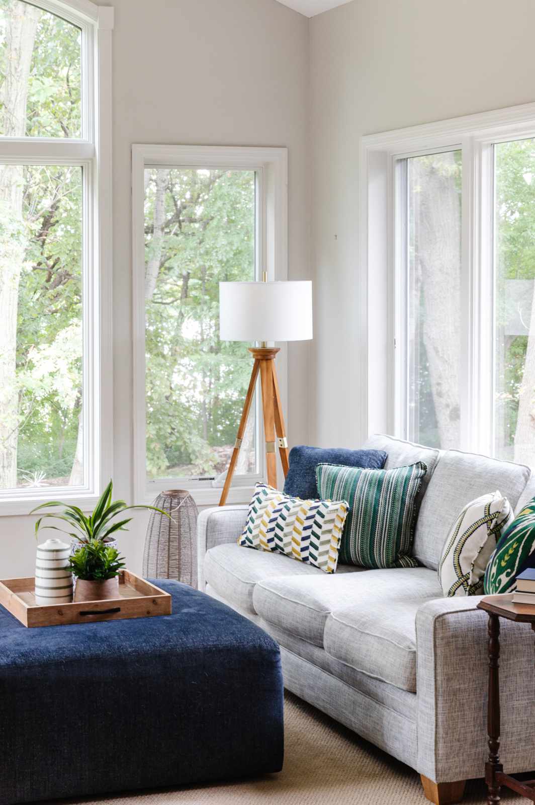 Gray sofa and blue ottoman coffee table in a sunroom with light gray walls